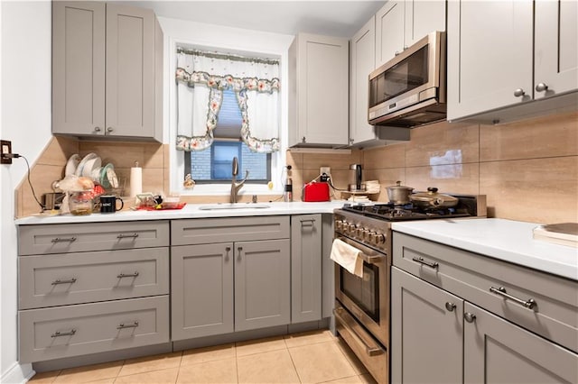 kitchen featuring a sink, light countertops, gray cabinetry, and stainless steel appliances