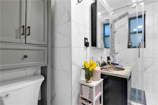 bathroom with vanity, tile walls, toilet, and a stall shower