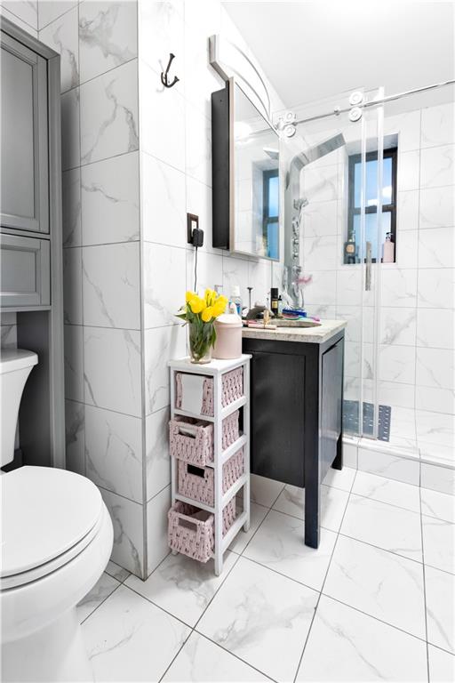 bathroom with vanity, tile walls, marble finish floor, and a stall shower