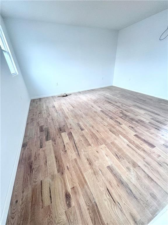 empty room with baseboards and light wood-type flooring