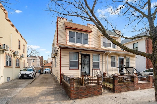 multi unit property with concrete driveway, a fenced front yard, and a chimney