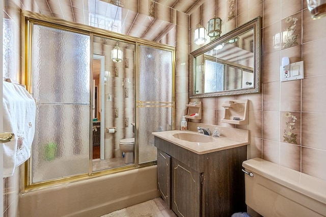 bathroom featuring bath / shower combo with glass door, toilet, tile walls, and vanity