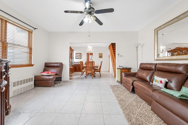 living area featuring radiator and ceiling fan with notable chandelier