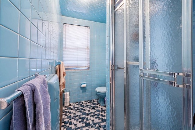 bathroom with toilet, tile walls, and a shower stall