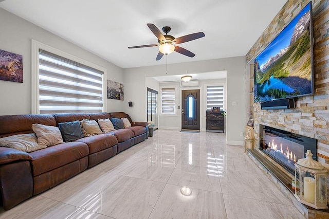 living room featuring a fireplace, baseboards, and a ceiling fan