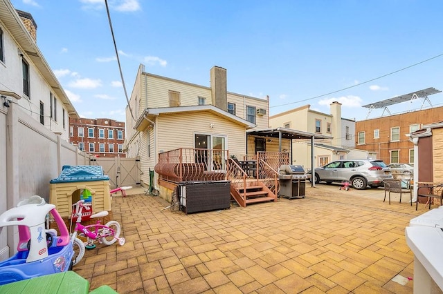 rear view of house featuring a patio, fence, a chimney, and a gate