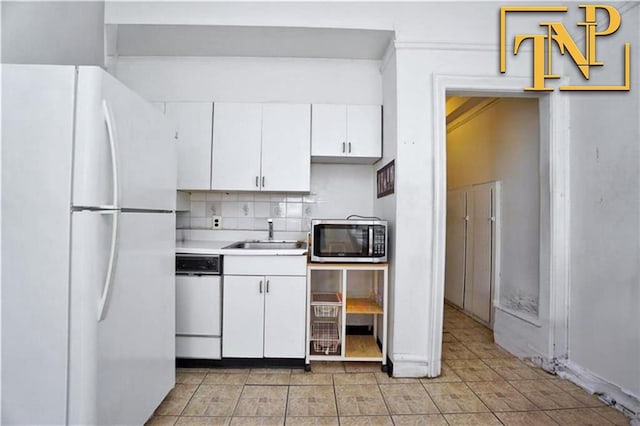 kitchen featuring a sink, stainless steel microwave, white cabinetry, freestanding refrigerator, and dishwasher