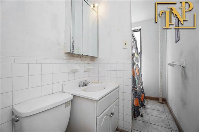 bathroom with tile walls, a wainscoted wall, toilet, tile patterned floors, and vanity