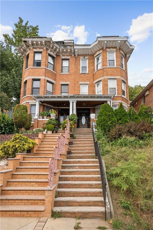 view of front of home featuring stairs and brick siding