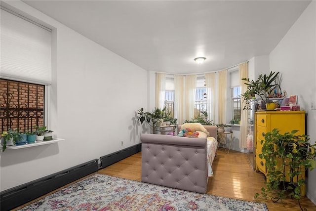 living area featuring a baseboard radiator, baseboards, and wood finished floors