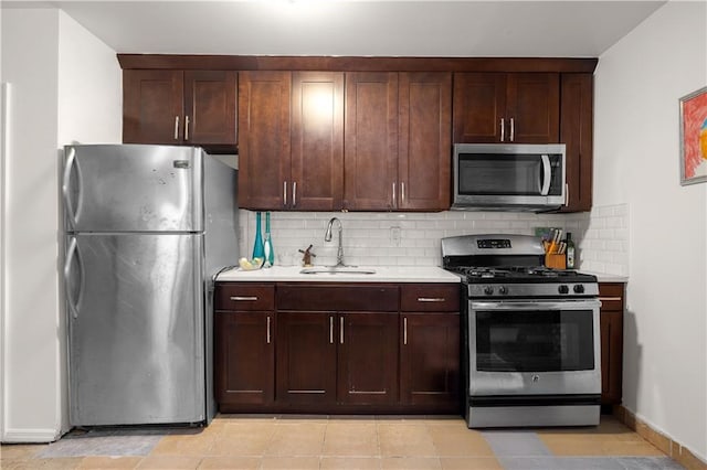 kitchen featuring a sink, stainless steel appliances, light countertops, dark brown cabinetry, and tasteful backsplash