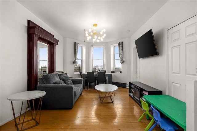 living room with an inviting chandelier, light wood-style flooring, cooling unit, and baseboards