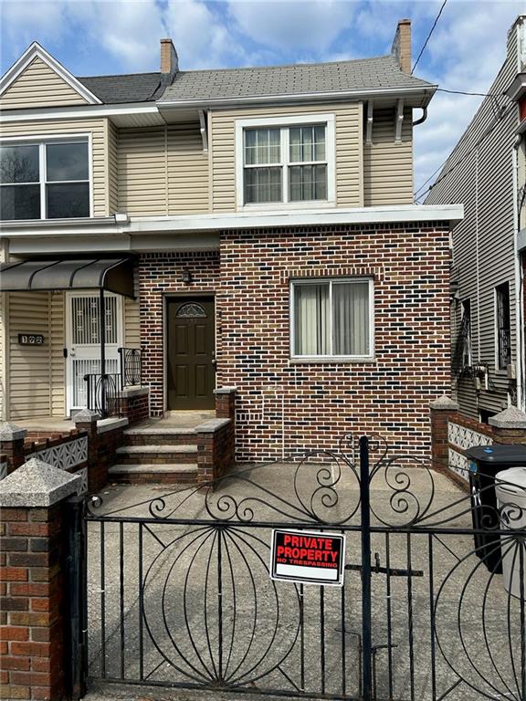 view of front of house featuring brick siding, a fenced front yard, and a gate