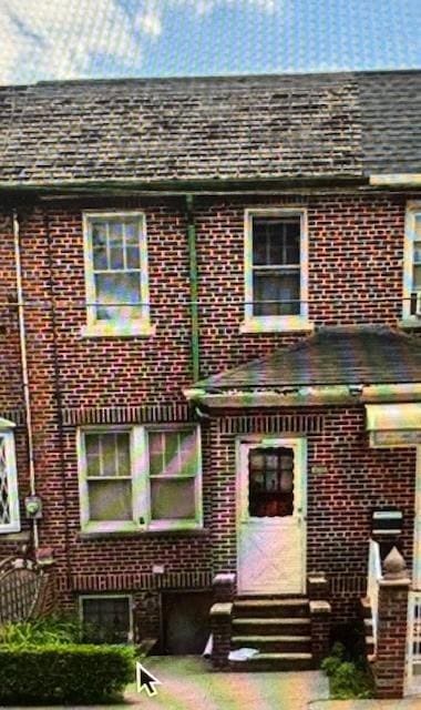 back of property with brick siding, entry steps, and a shingled roof