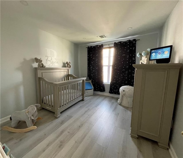 bedroom featuring visible vents, baseboards, and light wood finished floors