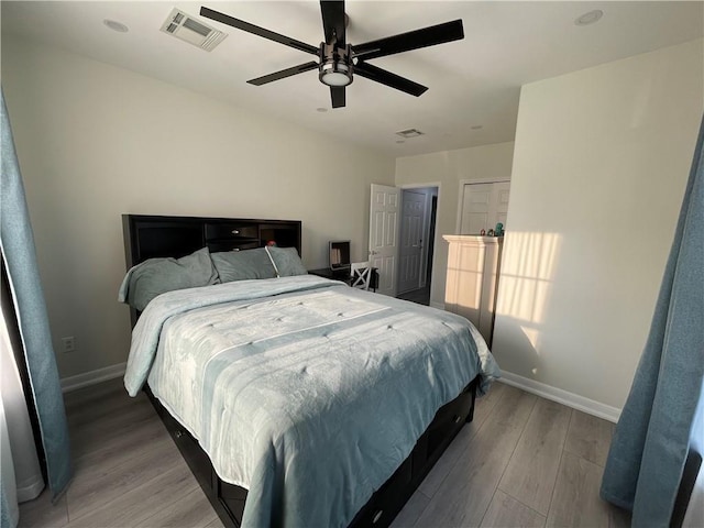 bedroom featuring visible vents, a ceiling fan, baseboards, and wood finished floors