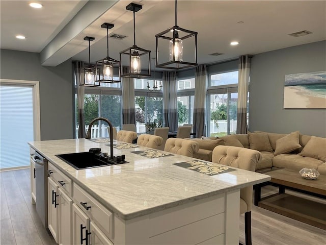 kitchen featuring visible vents, light wood-style flooring, a sink, dishwasher, and open floor plan