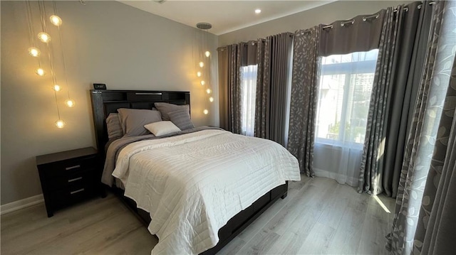 bedroom featuring light wood finished floors and baseboards