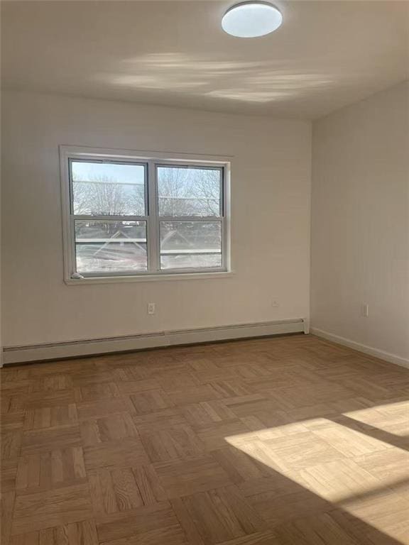 spare room featuring a baseboard heating unit and baseboards