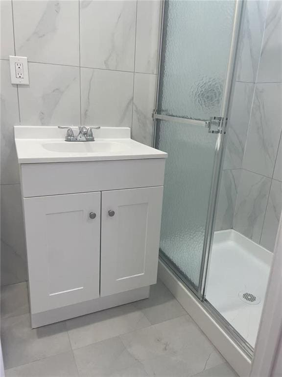 full bath featuring tile walls, a stall shower, and vanity