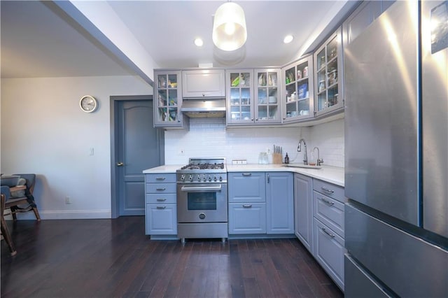 kitchen featuring under cabinet range hood, a sink, appliances with stainless steel finishes, light countertops, and decorative backsplash