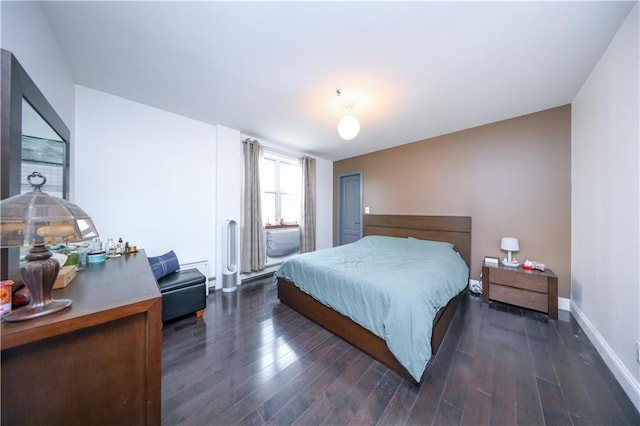 bedroom with a baseboard heating unit, baseboards, and wood finished floors