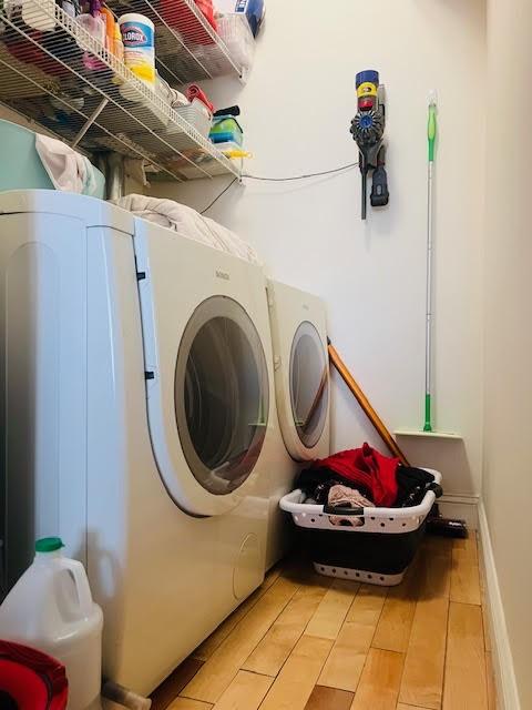 laundry area with washer and dryer, baseboards, laundry area, and light wood finished floors