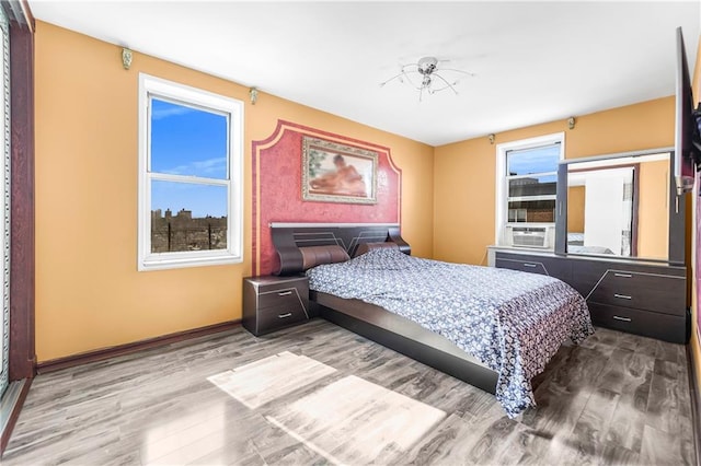 bedroom with cooling unit and wood finished floors