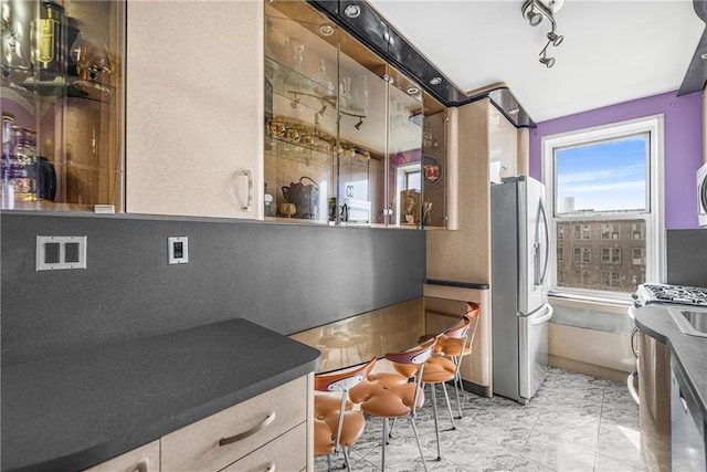 kitchen with dark countertops, track lighting, baseboards, appliances with stainless steel finishes, and marble finish floor