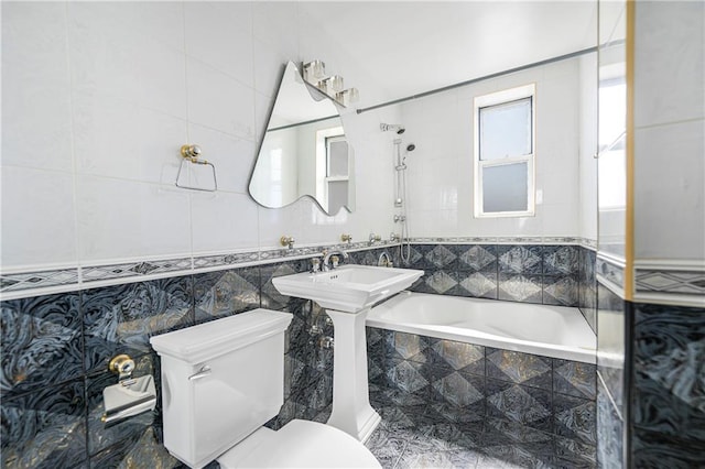 full bathroom with tiled shower / bath combo, toilet, and tile walls