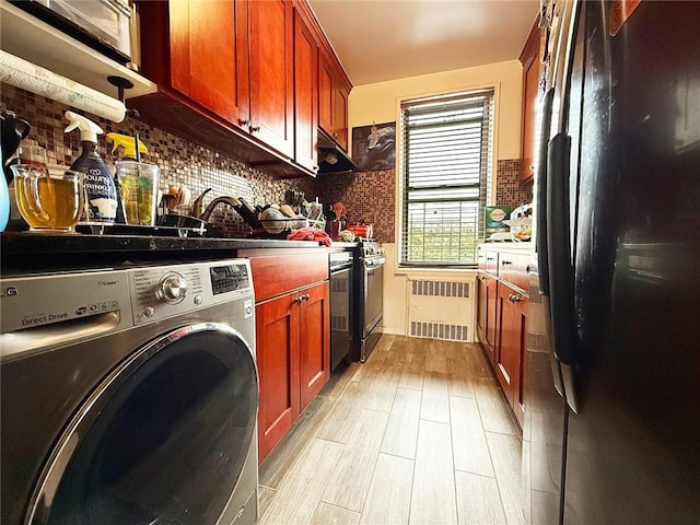 washroom with light wood-type flooring, radiator, washer / dryer, and laundry area