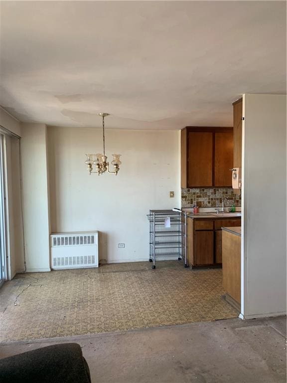 2652 Cropsey Ave Unit 15K, Brooklyn, NY 11214 - kitchen with brown cabinetry, radiator, tasteful backsplash, a chandelier, and pendant lighting