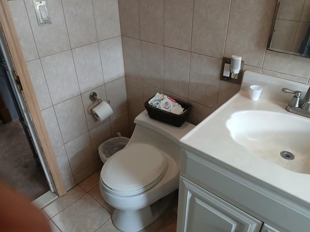 bathroom with tile walls, vanity, toilet, and tile patterned flooring