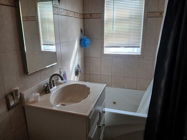 bathroom with tile walls, vanity, and shower / bath combination with curtain
