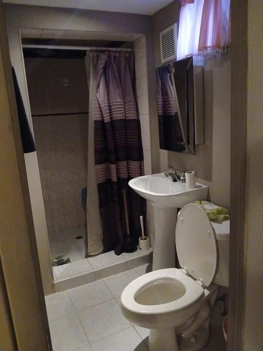 full bathroom with tile patterned flooring, toilet, and a stall shower