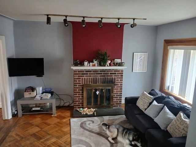 living area featuring rail lighting and a brick fireplace