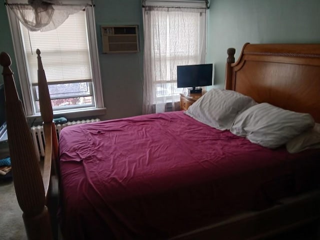 bedroom featuring multiple windows, an AC wall unit, and carpet flooring
