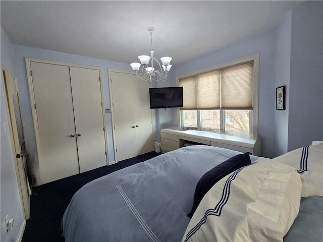 bedroom featuring a chandelier and multiple closets