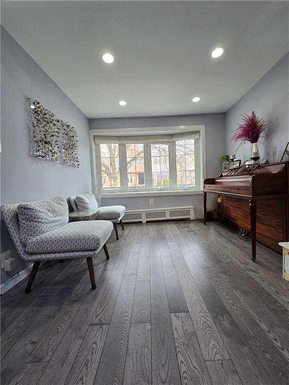 living area featuring baseboard heating, dark wood-style flooring, recessed lighting, and baseboards