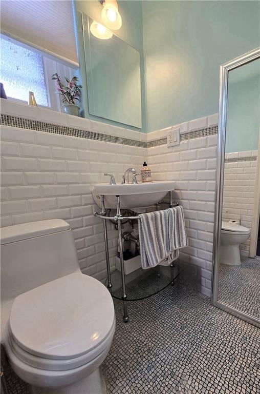 full bathroom featuring toilet, tile walls, wainscoting, a shower stall, and tile patterned flooring