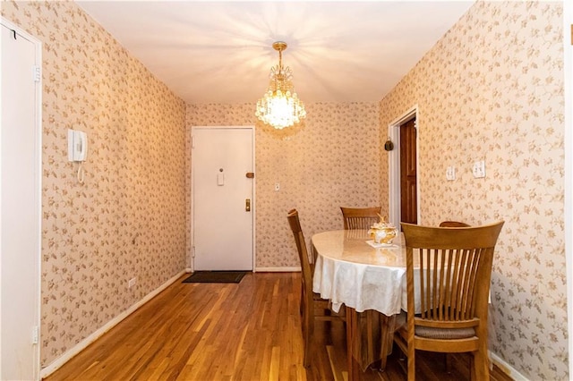 dining space featuring wood finished floors and wallpapered walls