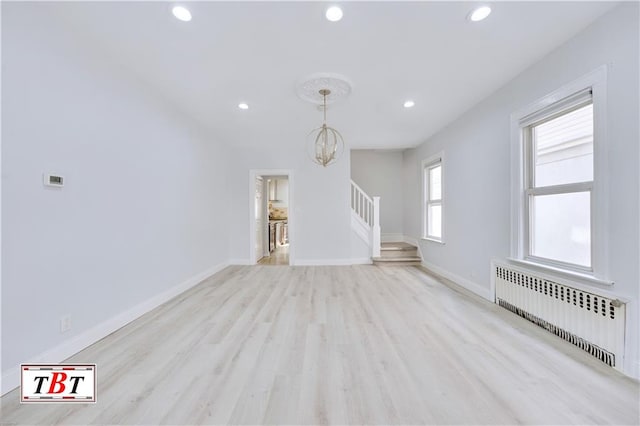 unfurnished living room with radiator heating unit, a chandelier, recessed lighting, light wood finished floors, and baseboards