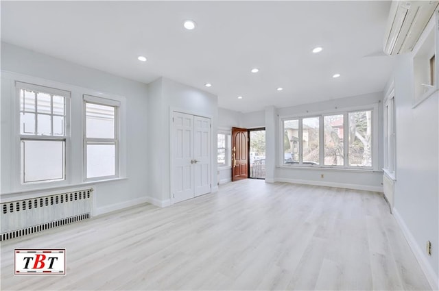 unfurnished living room with radiator, light wood-type flooring, healthy amount of natural light, and recessed lighting