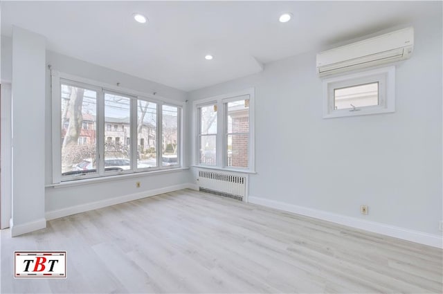 unfurnished room with radiator, an AC wall unit, wood finished floors, baseboards, and recessed lighting
