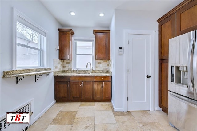 kitchen featuring stainless steel fridge, a sink, baseboards, light stone counters, and recessed lighting