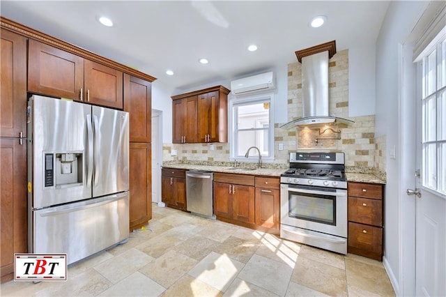 kitchen featuring appliances with stainless steel finishes, wall chimney exhaust hood, a wall mounted AC, a sink, and tasteful backsplash