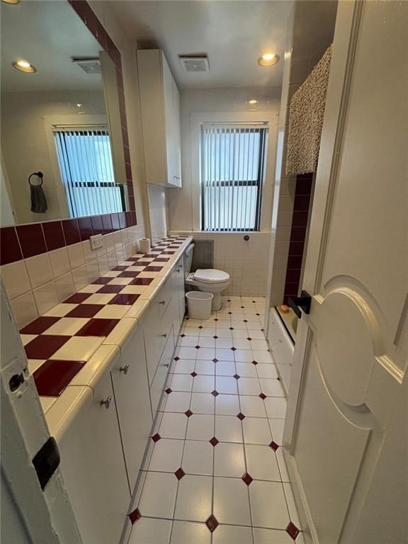 full bathroom with vanity, visible vents, walk in shower, tile patterned floors, and toilet