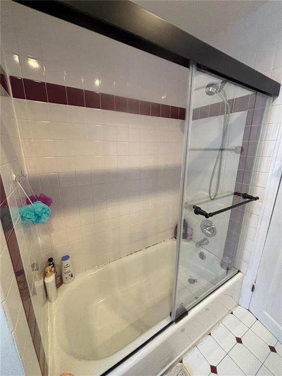 full bath with combined bath / shower with glass door and tile patterned flooring