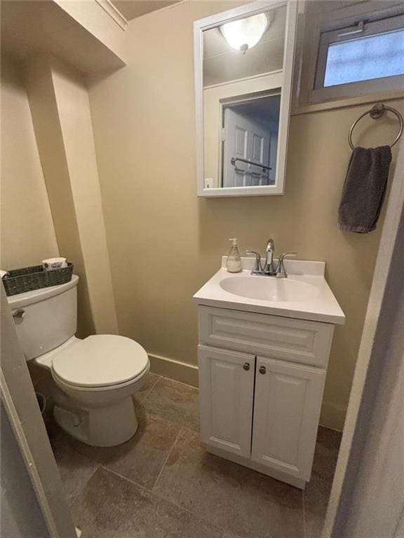 bathroom featuring baseboards, stone finish flooring, toilet, and vanity