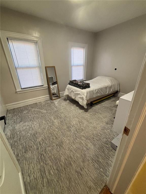 bedroom featuring multiple windows, baseboards, and carpet